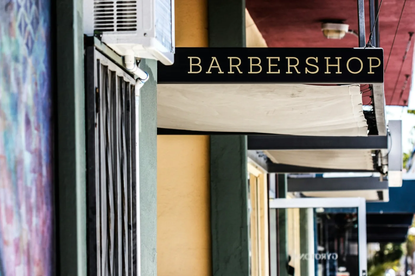 Barbería de calle con su toldo y su rótulo