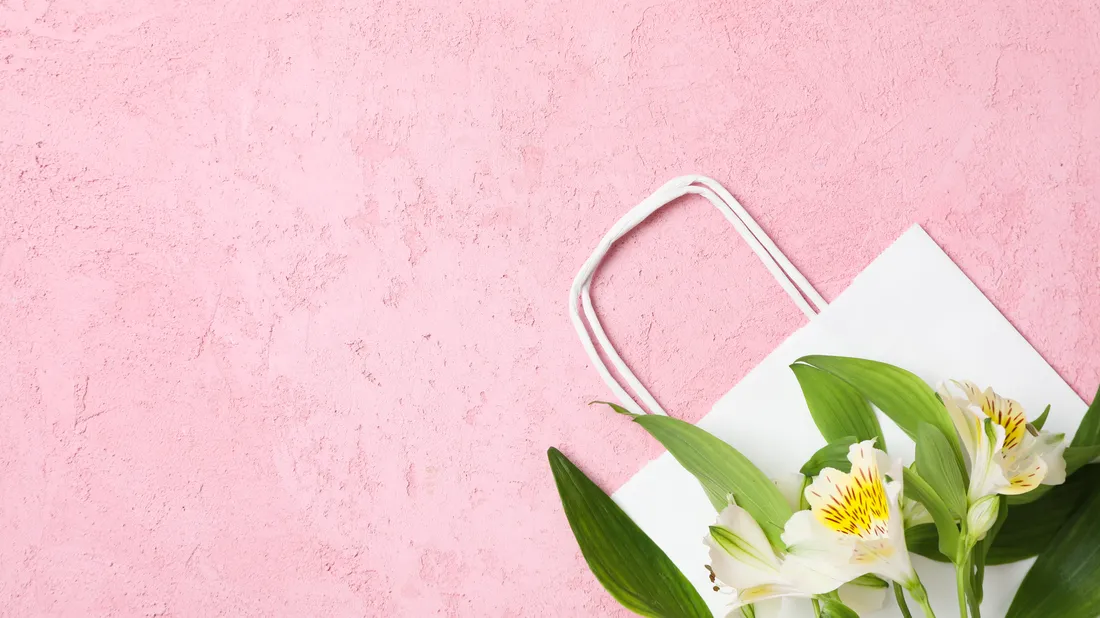 Una bolsa de la compra con flores, sobre fondo rosa