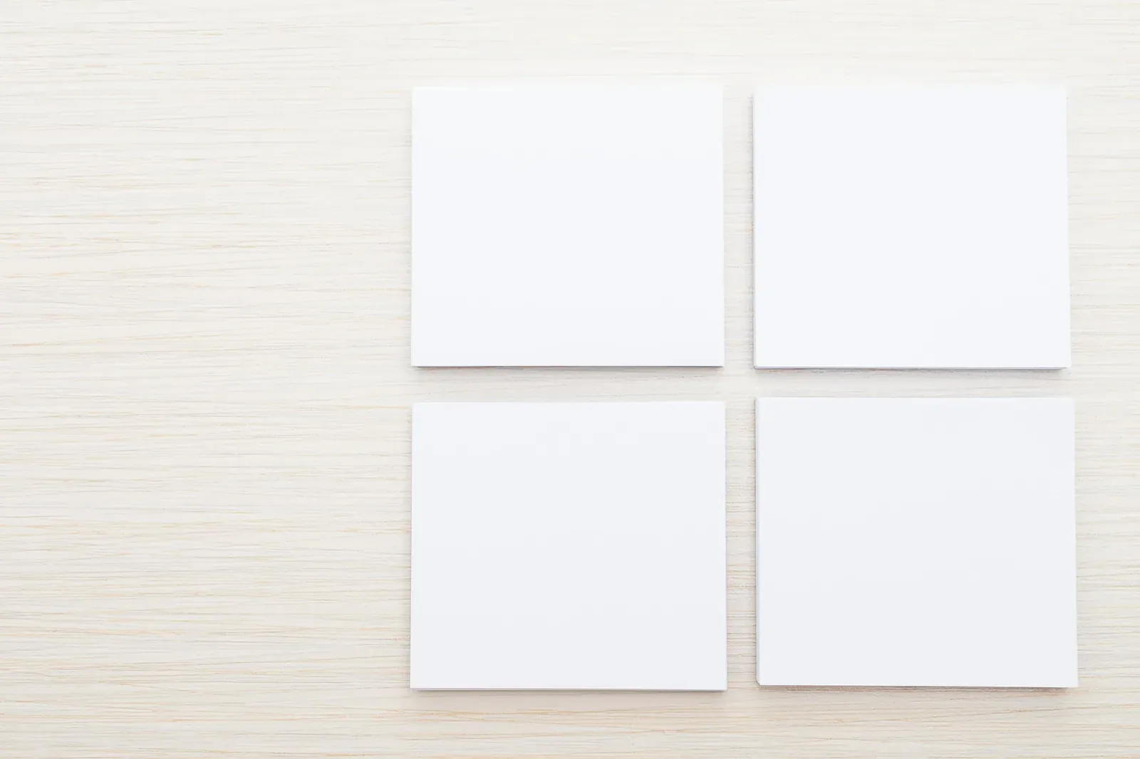 Tres hojas de papel en formato cuadrado, horizontal y vertical sobre una superficie color arena