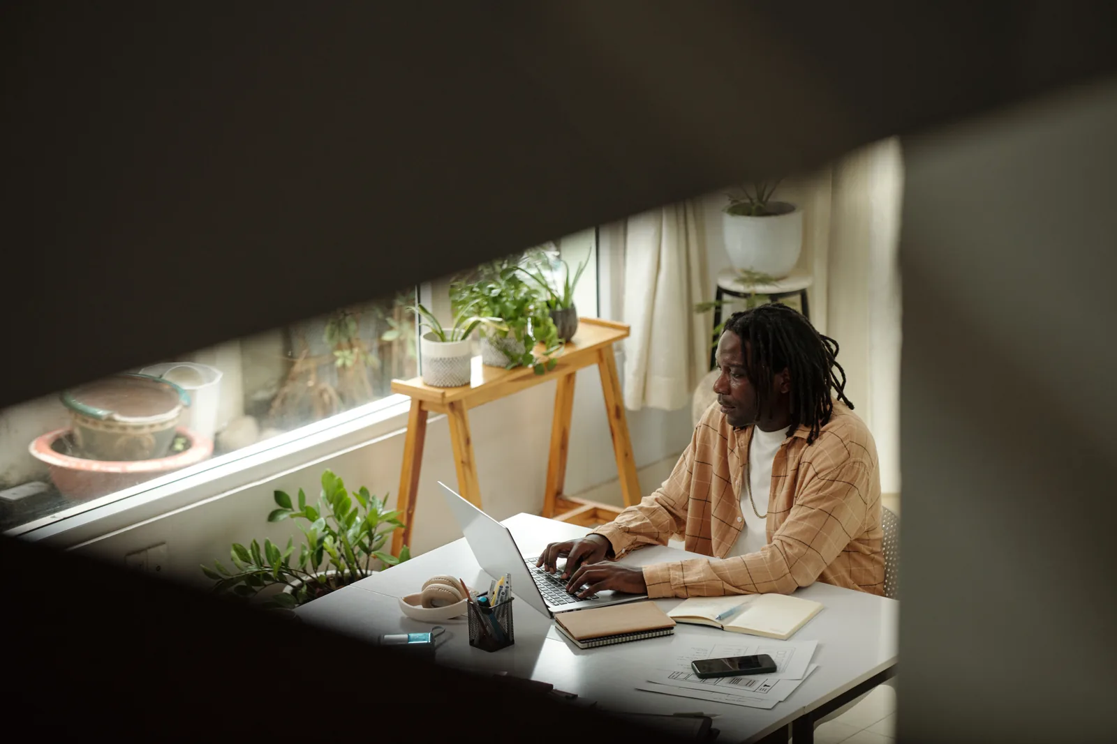 Un diseñador trabaja con el portátil en su escritorio, junto a la ventana
